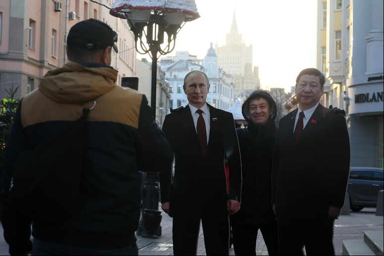Homem posa entre bonecos de cartaz de Putin e Xi em Moscou © ANSA/EPA