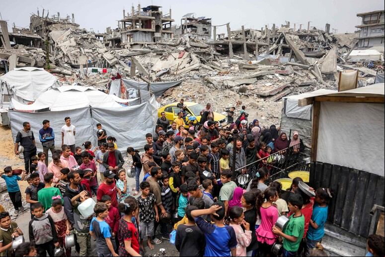 Pessoas fazendo fila com as para receber refeições de caridade na Faixa de Gaza © ANSA/AFP