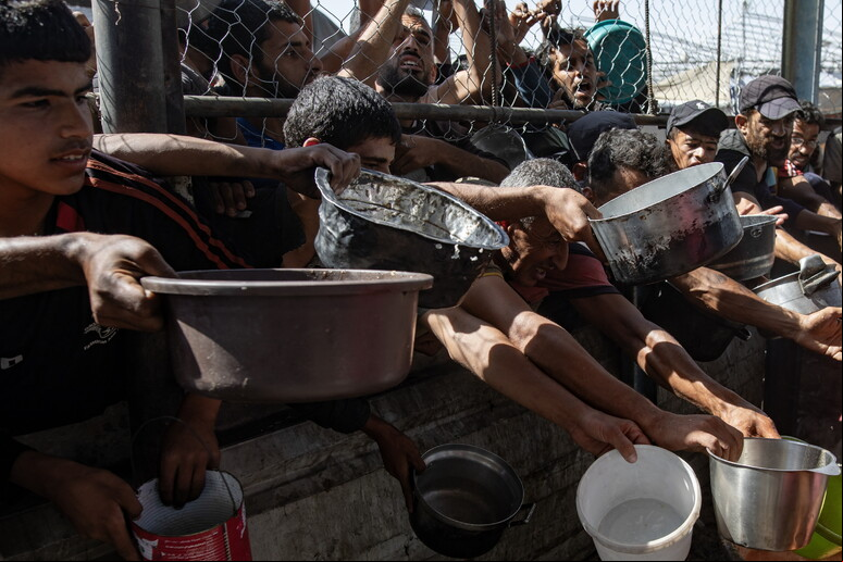 Palestinos em fila de distribuição de comida em Khan Younis, no sul de Gaza - TODOS OS DIREITOS RESERVADOS
